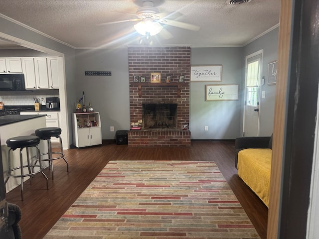 living room featuring crown molding, a ceiling fan, a textured ceiling, and dark wood-type flooring