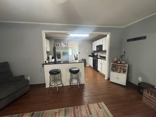 kitchen with a peninsula, dark countertops, dark wood-type flooring, white cabinetry, and black appliances
