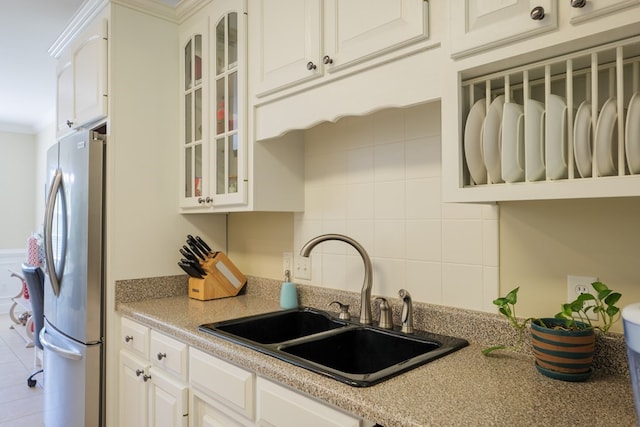 kitchen featuring white cabinetry, stainless steel fridge, sink, and crown molding