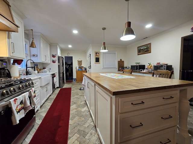 kitchen featuring white cabinetry, wooden counters, stainless steel appliances, and a center island