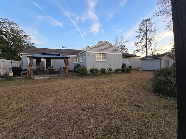 back house at dusk featuring a yard, a gazebo, and a patio area