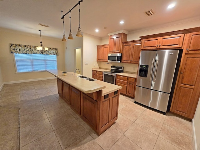 kitchen with decorative light fixtures, an island with sink, sink, ornamental molding, and stainless steel appliances