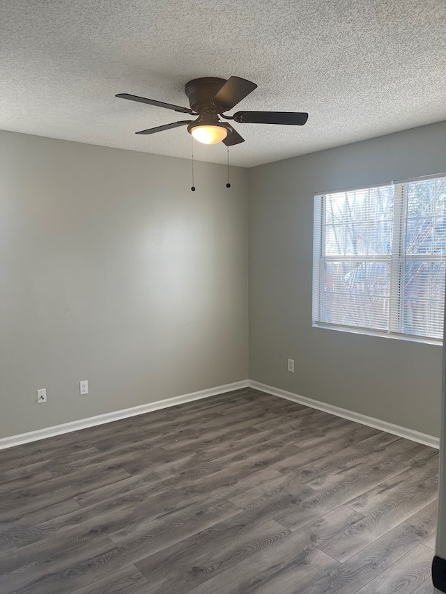 spare room with a textured ceiling, ceiling fan, and dark wood-type flooring