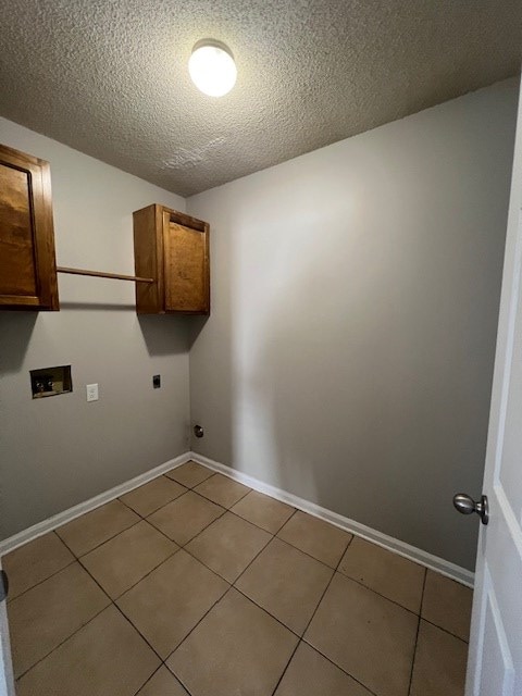 laundry area with electric dryer hookup, cabinets, washer hookup, a textured ceiling, and light tile patterned flooring