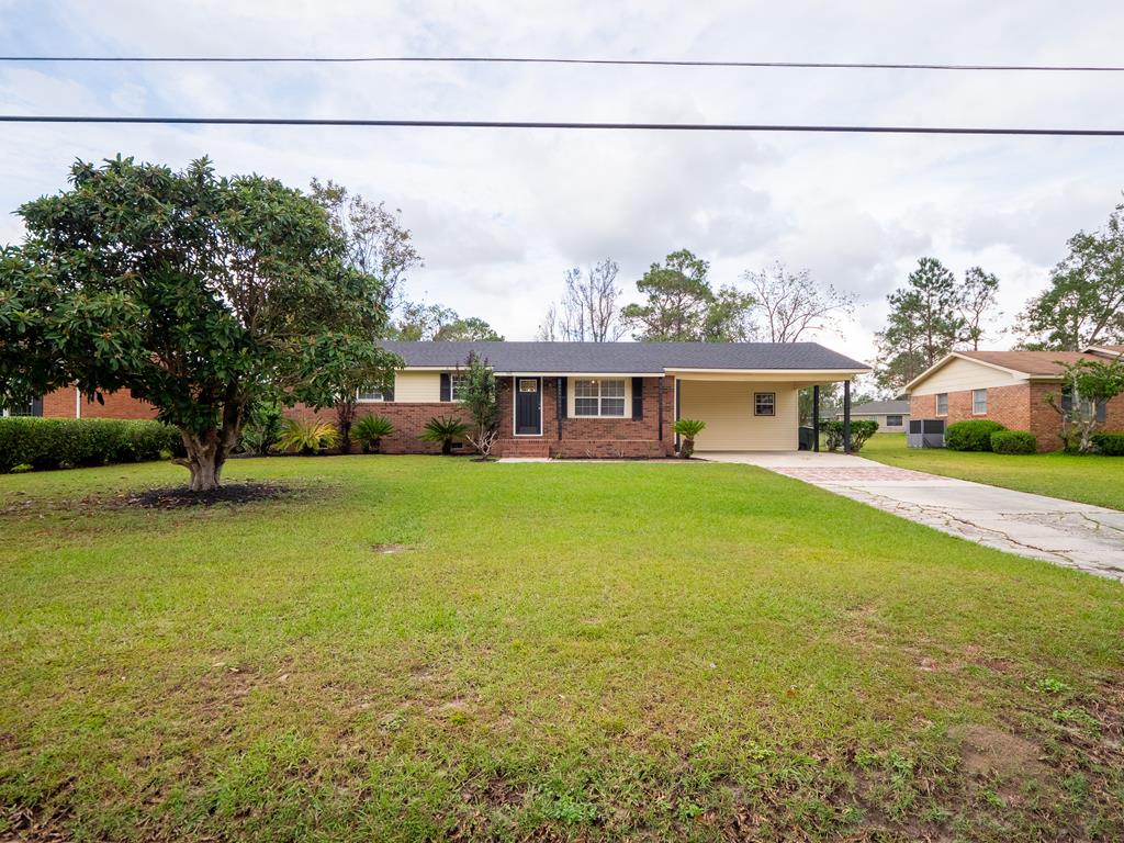 single story home with a front lawn and a carport