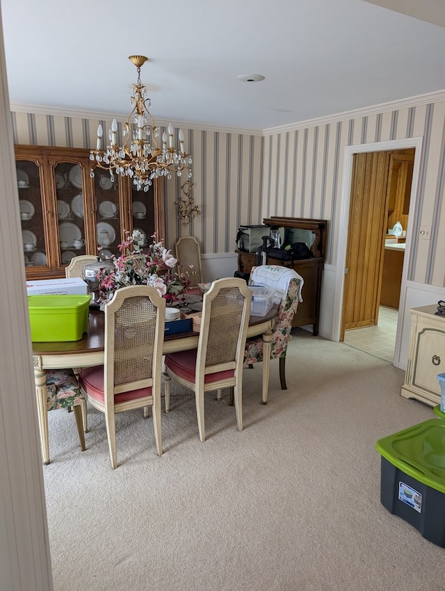 dining space with carpet floors, a notable chandelier, ornamental molding, and wallpapered walls