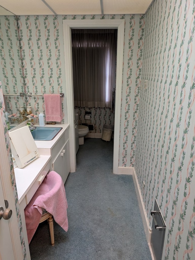 bathroom featuring carpet flooring, vanity, toilet, and wallpapered walls