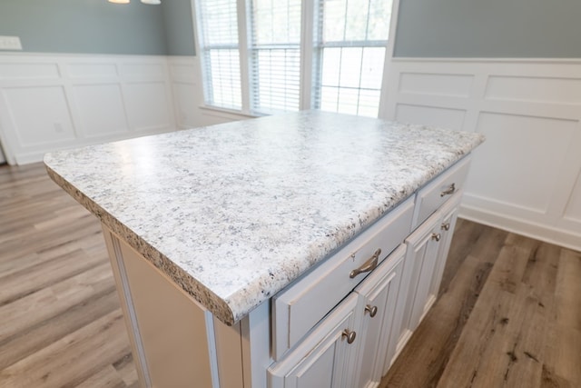 details featuring a center island, wood-type flooring, and white cabinetry