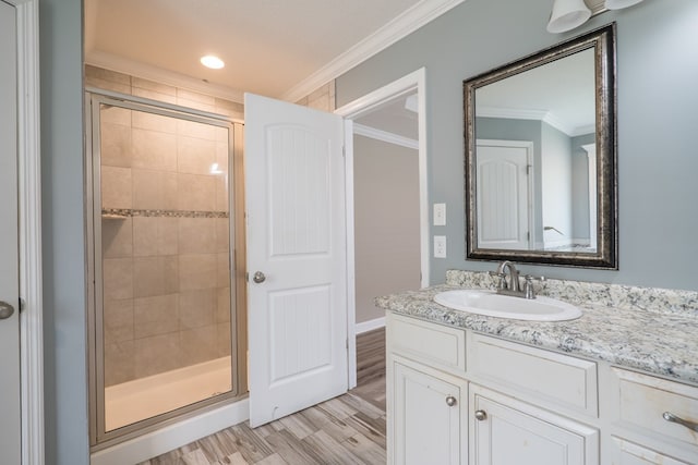 bathroom featuring vanity, hardwood / wood-style flooring, walk in shower, and crown molding