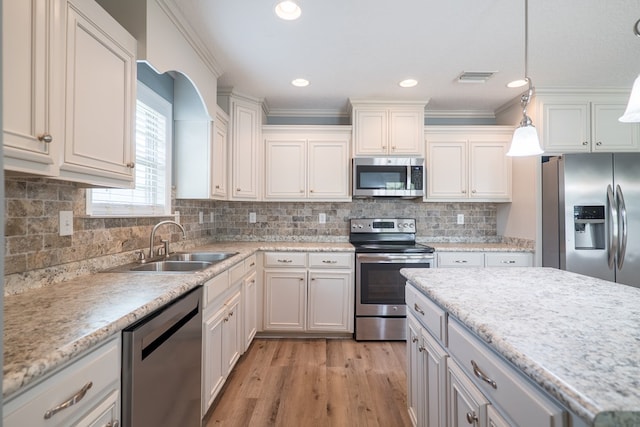 kitchen with pendant lighting, decorative backsplash, ornamental molding, and appliances with stainless steel finishes