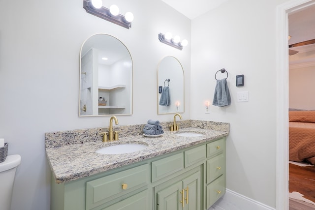 full bathroom featuring a sink, baseboards, double vanity, and ensuite bath