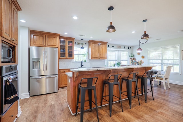kitchen with brown cabinetry, light wood-style flooring, a breakfast bar, and stainless steel appliances