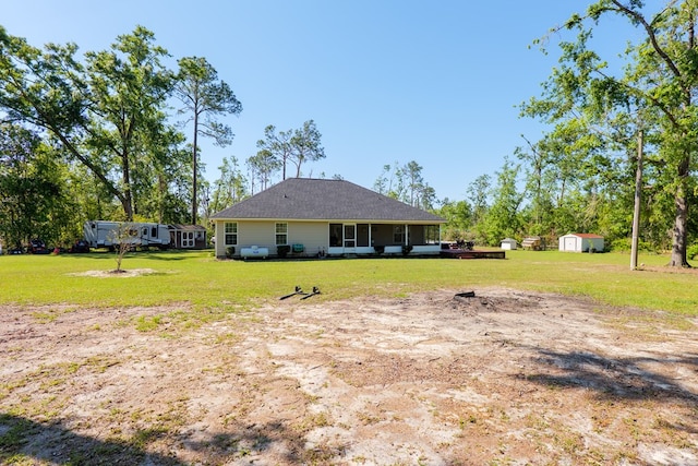 rear view of house with a yard, an outdoor structure, and a storage unit