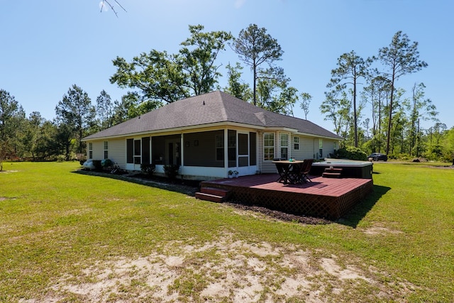 back of property with an outdoor hot tub, a wooden deck, a sunroom, and a lawn