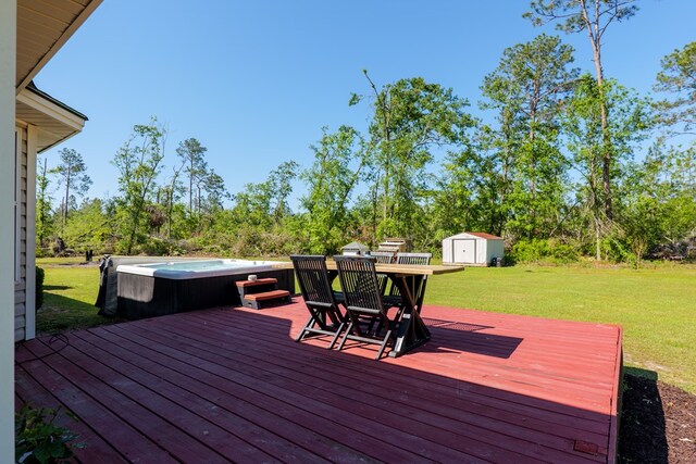 wooden terrace featuring an outdoor structure, a lawn, a shed, and a hot tub