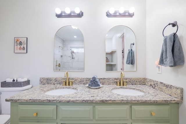 full bathroom featuring a sink, toilet, double vanity, and tiled shower