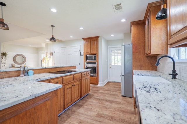 kitchen with visible vents, recessed lighting, a sink, stainless steel appliances, and brown cabinets