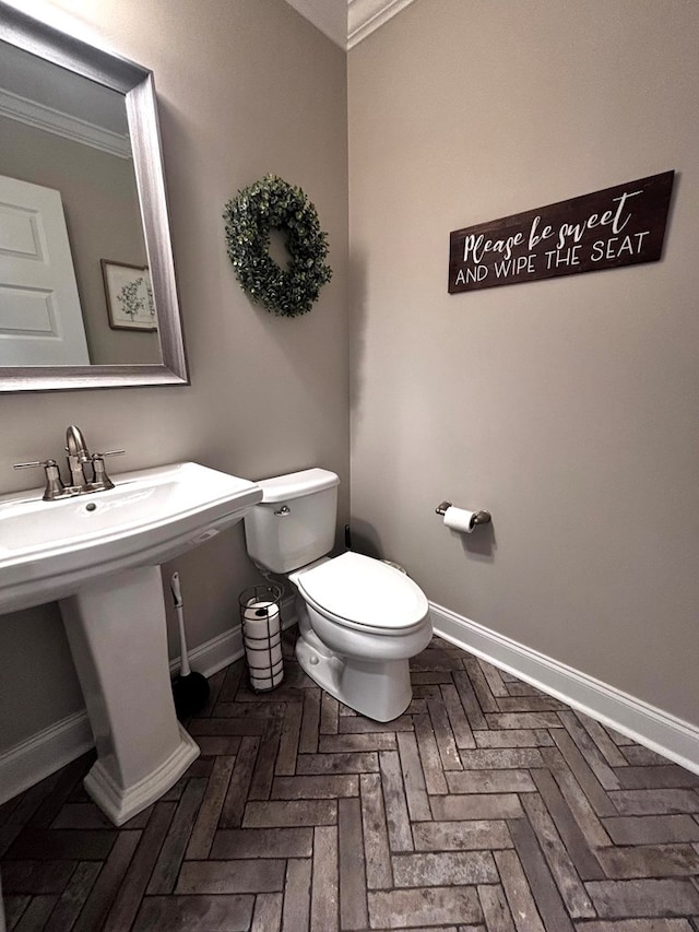 bathroom featuring toilet, baseboards, and crown molding