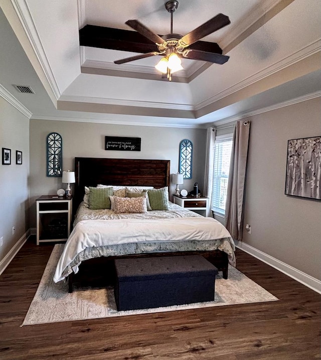 bedroom with a tray ceiling, dark wood-style flooring, visible vents, baseboards, and crown molding