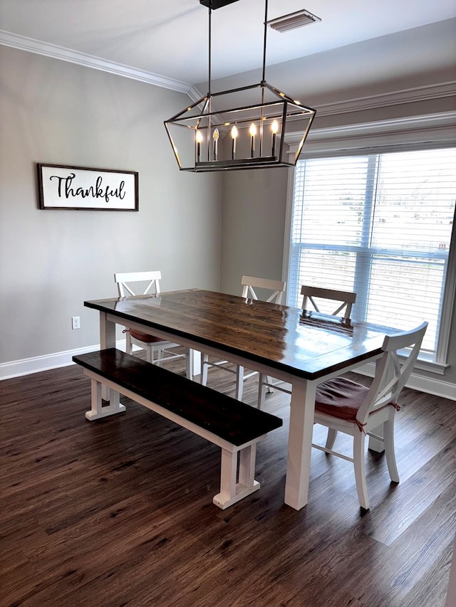 dining area featuring a chandelier, dark wood-type flooring, crown molding, visible vents, and baseboards