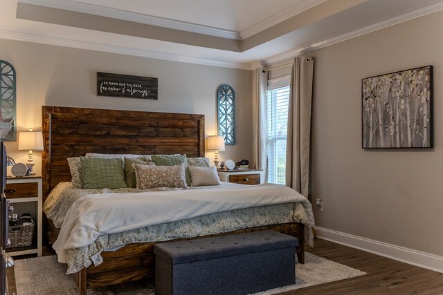 bedroom featuring baseboards, wood finished floors, crown molding, and a raised ceiling