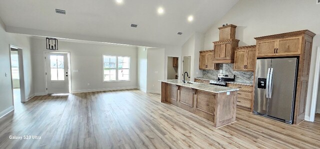 kitchen featuring appliances with stainless steel finishes, a chandelier, decorative backsplash, a kitchen island with sink, and light hardwood / wood-style floors