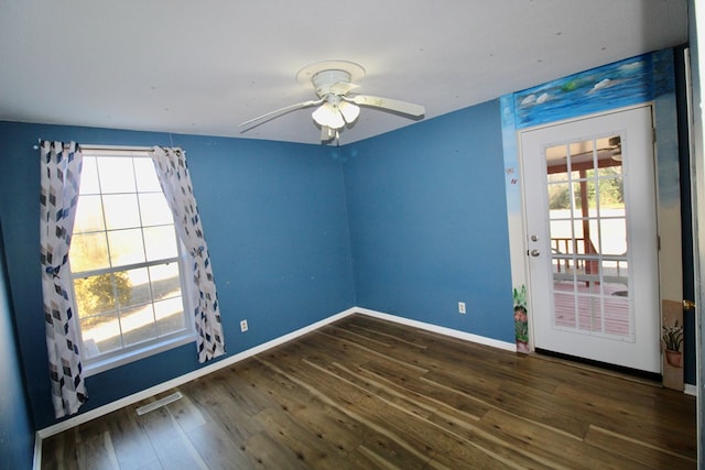 empty room with a healthy amount of sunlight, dark hardwood / wood-style floors, and ceiling fan