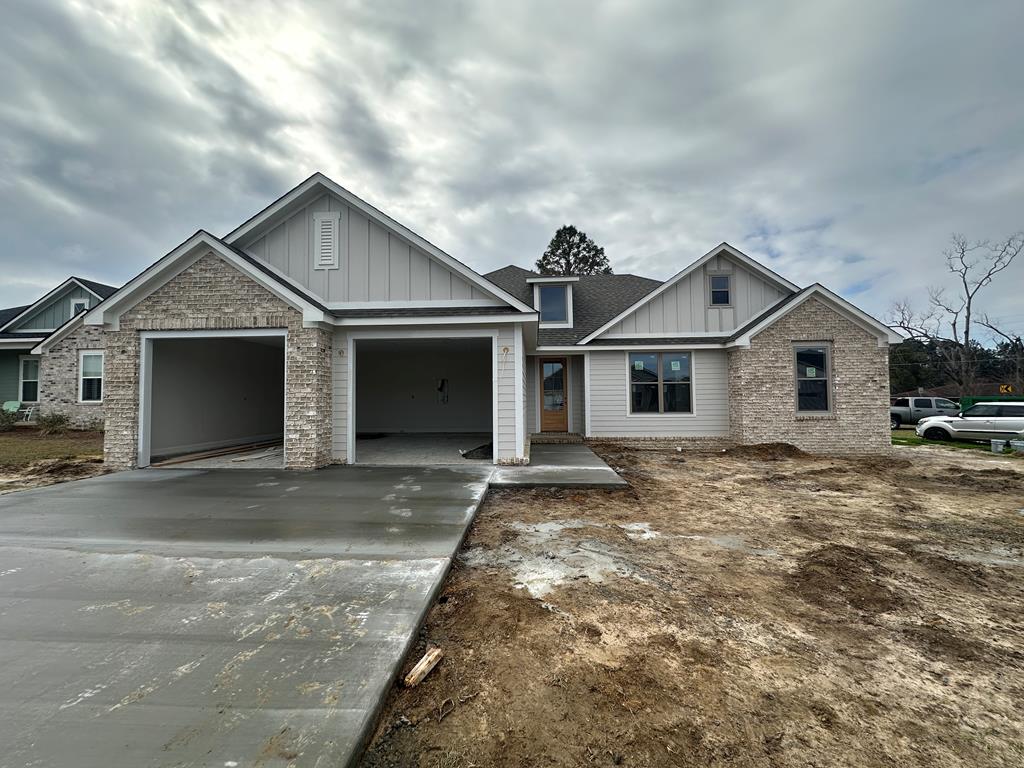 craftsman house with a garage, brick siding, board and batten siding, and concrete driveway