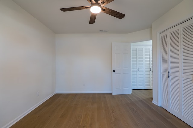 unfurnished bedroom featuring wood finished floors, visible vents, a closet, and baseboards