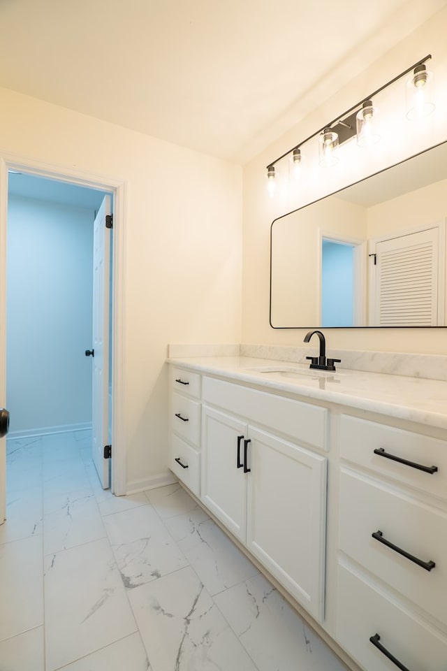 bathroom with marble finish floor, vanity, and baseboards