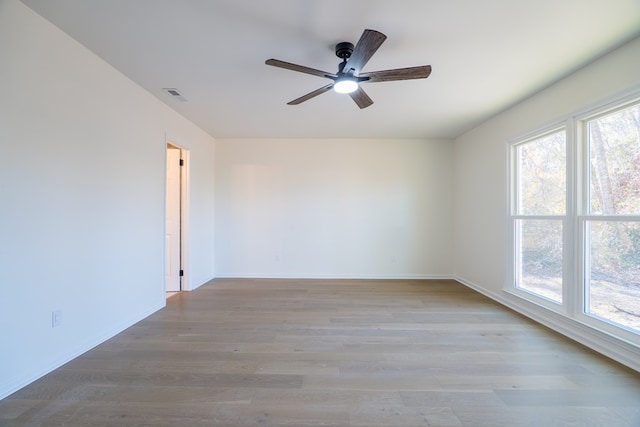 unfurnished room with a wealth of natural light, visible vents, baseboards, and wood finished floors