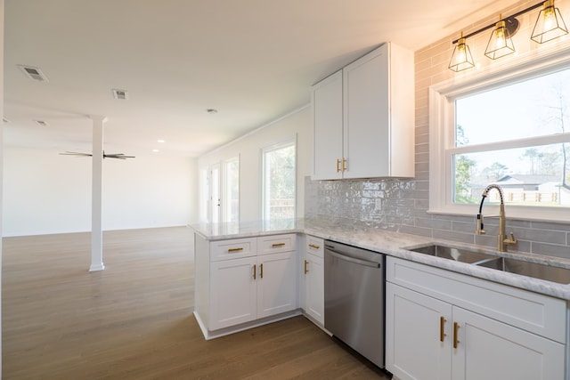 kitchen with visible vents, a sink, stainless steel dishwasher, a peninsula, and decorative backsplash