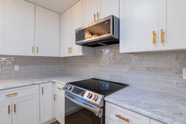 kitchen with decorative backsplash, white cabinets, light stone counters, and stainless steel appliances