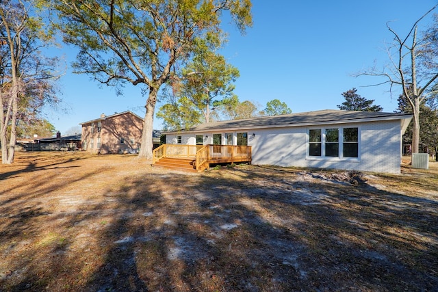 rear view of house with brick siding, a wooden deck, and central AC