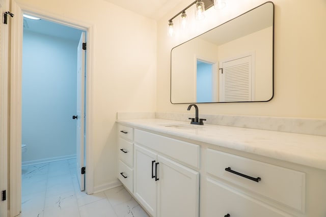 bathroom featuring vanity, toilet, baseboards, and marble finish floor