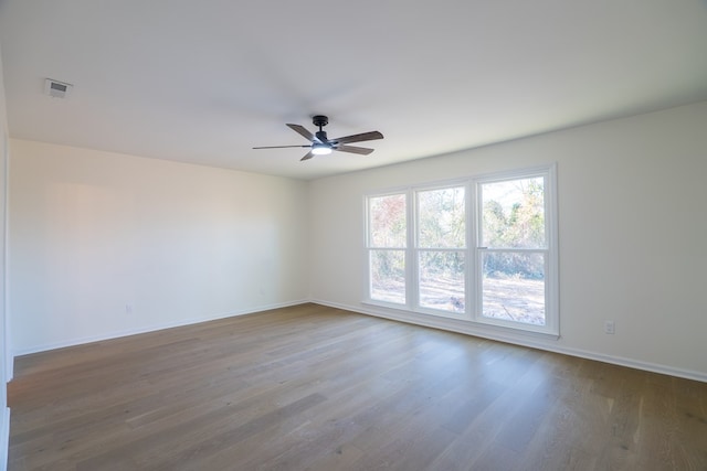 unfurnished room with visible vents, baseboards, wood finished floors, and a ceiling fan