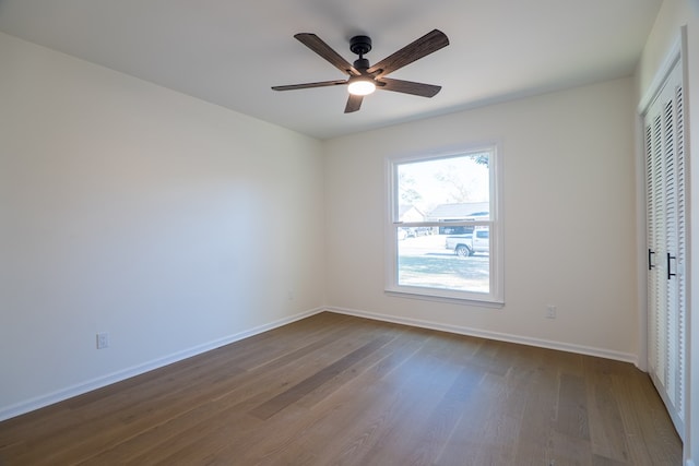 unfurnished bedroom with a closet, a ceiling fan, baseboards, and dark wood-style flooring