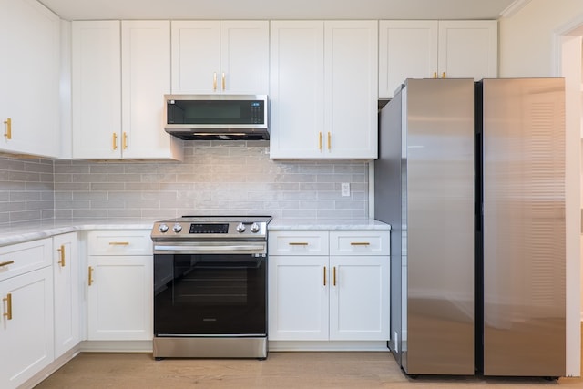 kitchen featuring decorative backsplash, white cabinetry, stainless steel appliances, and light wood-type flooring