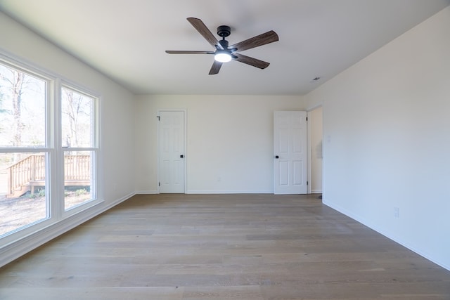 spare room featuring baseboards, wood finished floors, and a ceiling fan