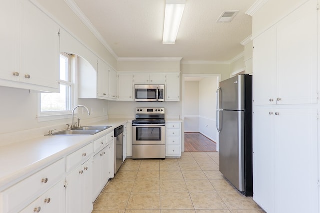 kitchen with light tile patterned floors, stainless steel appliances, ornamental molding, and a sink