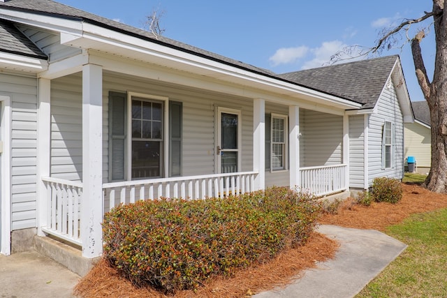 entrance to property with covered porch and roof with shingles