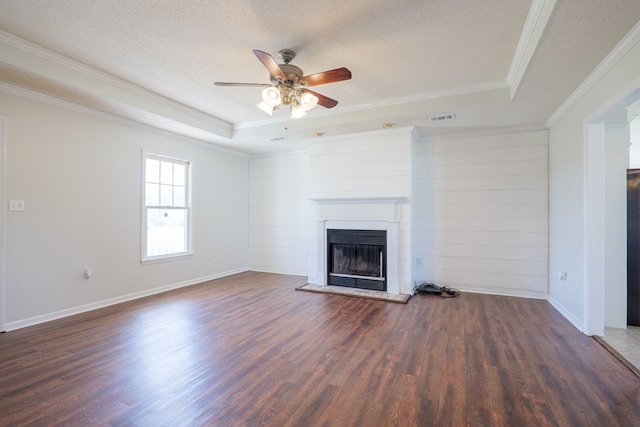 unfurnished living room featuring visible vents, a fireplace with raised hearth, a raised ceiling, wood finished floors, and a textured ceiling