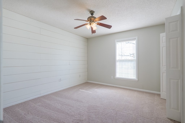 spare room with carpet flooring, ceiling fan, a textured ceiling, and baseboards