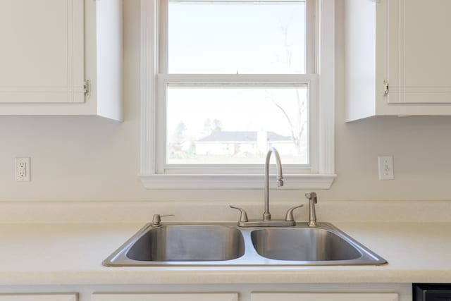 kitchen featuring light countertops, a sink, and white cabinetry