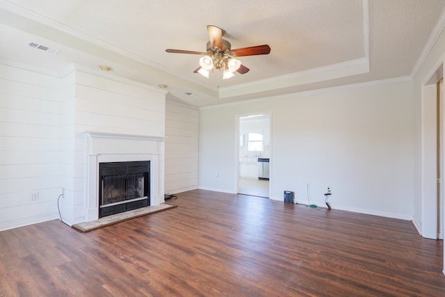 unfurnished living room featuring visible vents, a fireplace with raised hearth, wood finished floors, a tray ceiling, and a textured ceiling