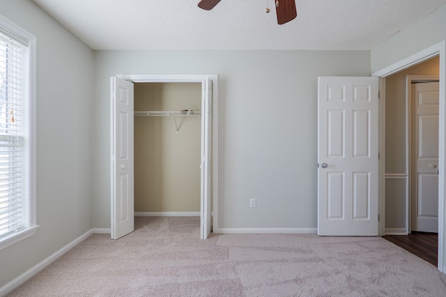 unfurnished bedroom featuring baseboards, a ceiling fan, a textured ceiling, carpet flooring, and a closet