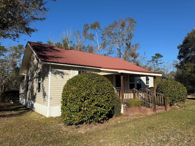 view of side of property featuring covered porch and a yard