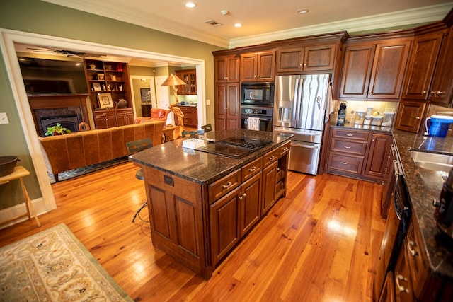 4059 Live Oaks Cir, Valdosta, GA 31601 - kitchen with black appliances, crown molding, light wood-style floors, a kitchen island, and a premium fireplace