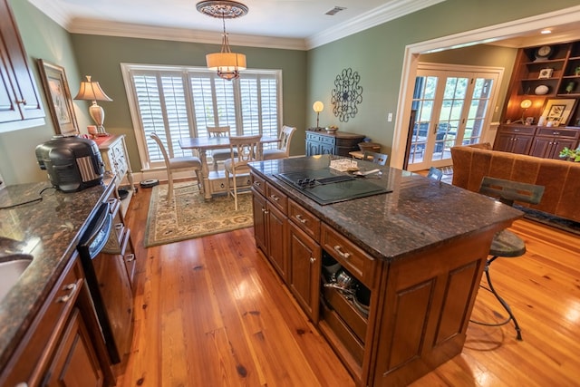 4059 Live Oaks Cir, Valdosta, GA 31601 - kitchen with brown cabinetry, light wood finished floors, dishwashing machine, a breakfast bar area, and healthy amount of natural light