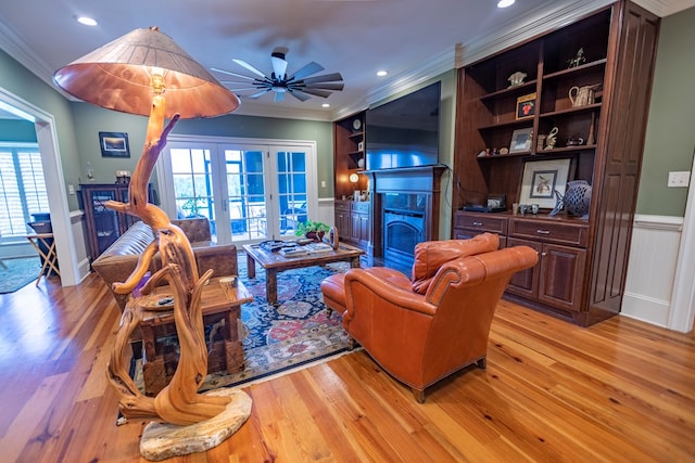 4059 Live Oaks Cir, Valdosta, GA 31601 - living room with french doors, crown molding, a fireplace with flush hearth, a wainscoted wall, and light wood-style flooring